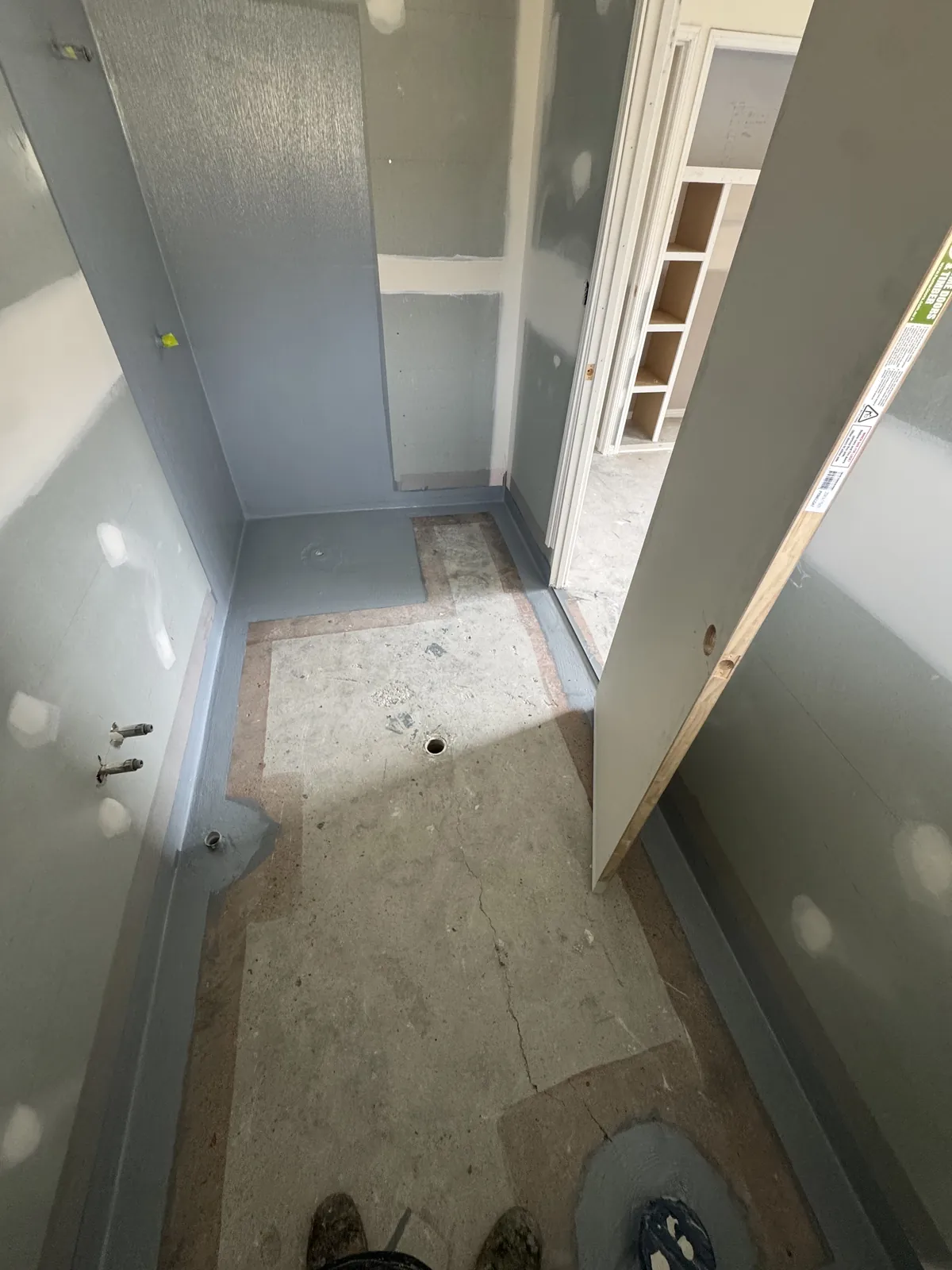 Narrow bathroom with membrane up the shower walls and around the floor perimeter, penetrations sealed before tiling