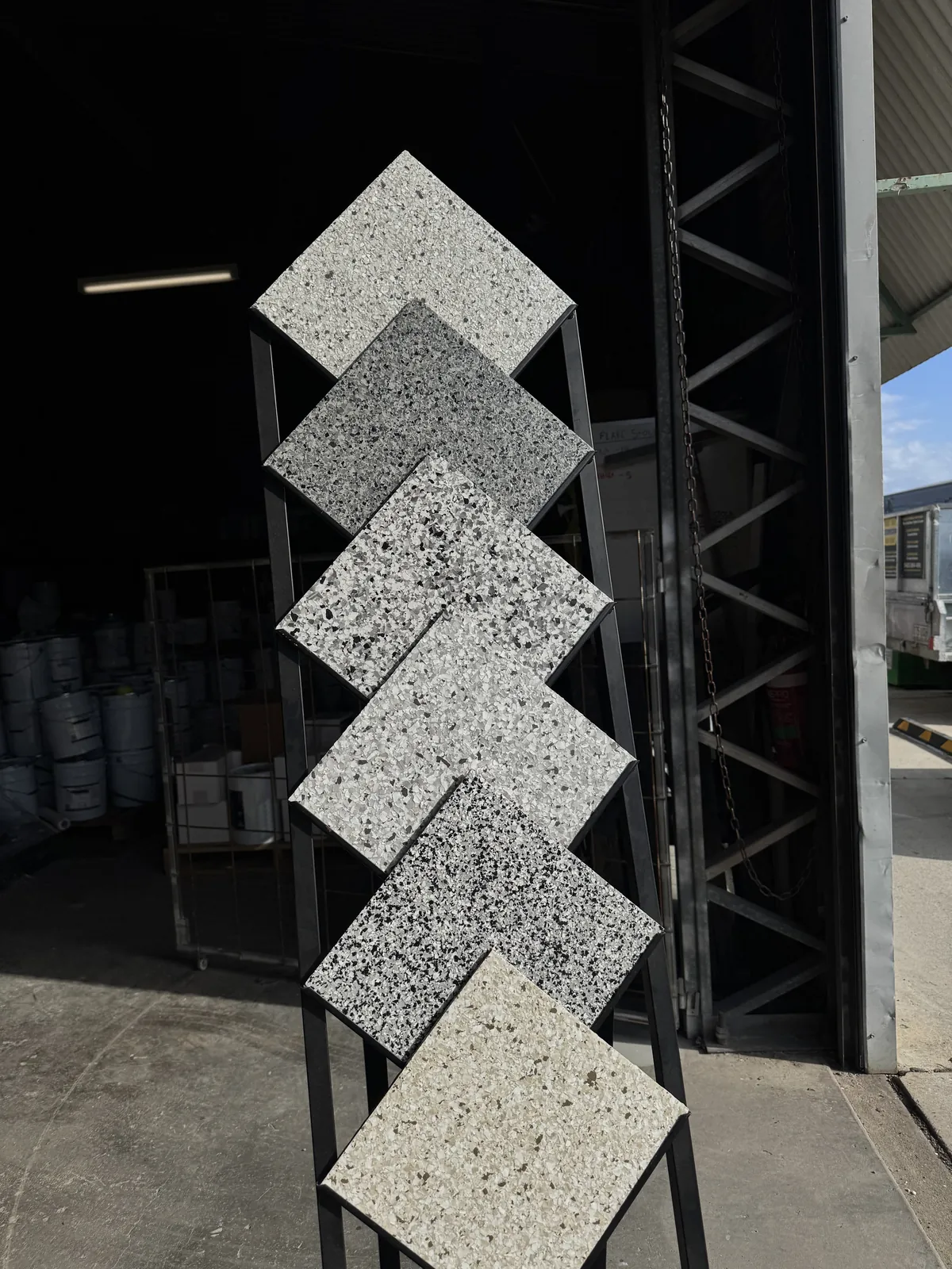 Flake epoxy sample boards in a range of grey, black and white blends on a display stand