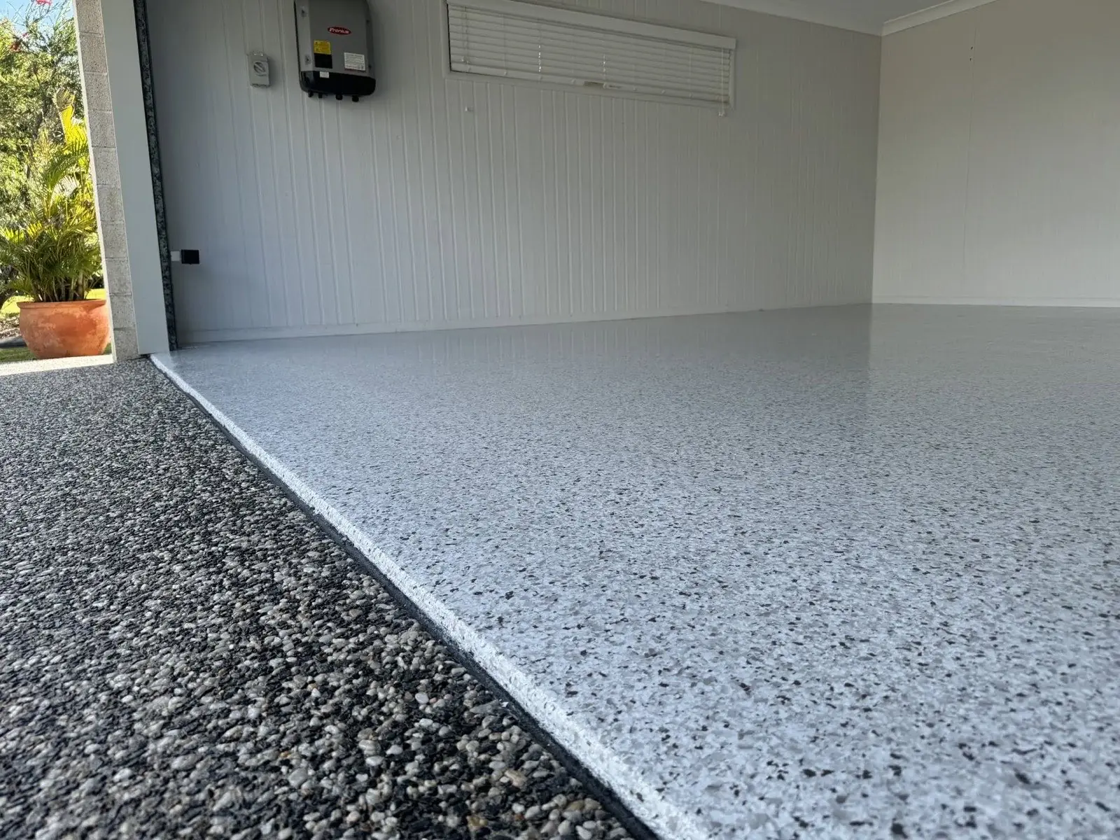 Low view of a grey flake epoxy garage floor finished in a clean straight line at the roller door