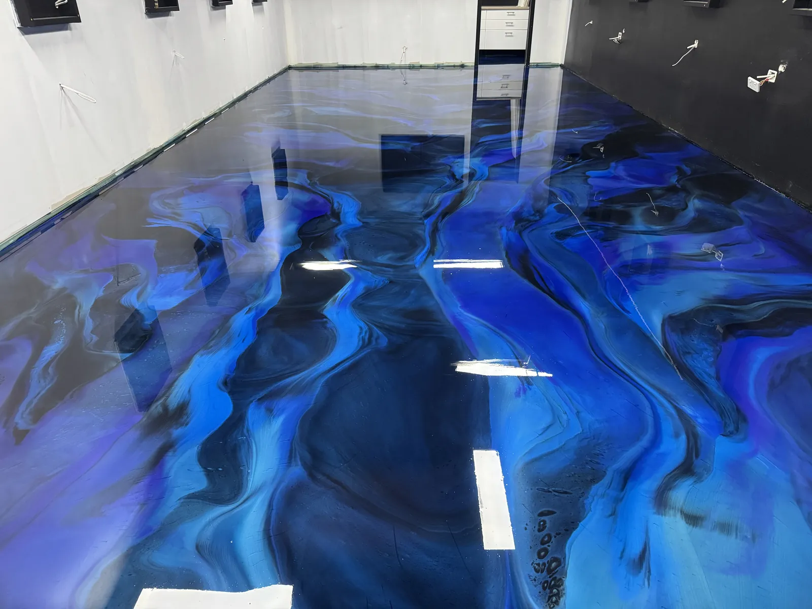 Wide view of a blue and black metallic epoxy floor with a glass-like finish across a large commercial space