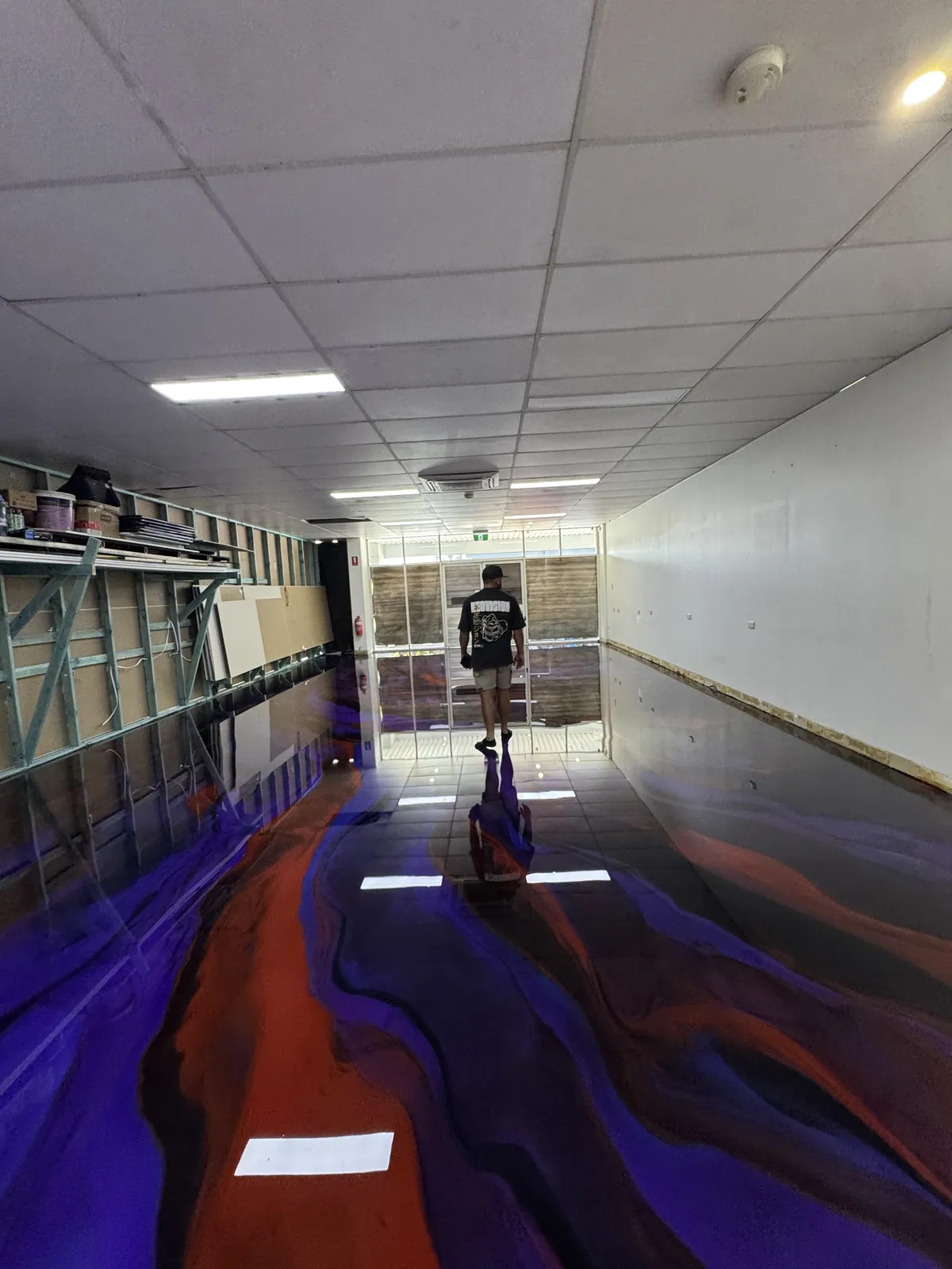 Long commercial tenancy with a purple, orange and black metallic epoxy floor reflecting the ceiling lights