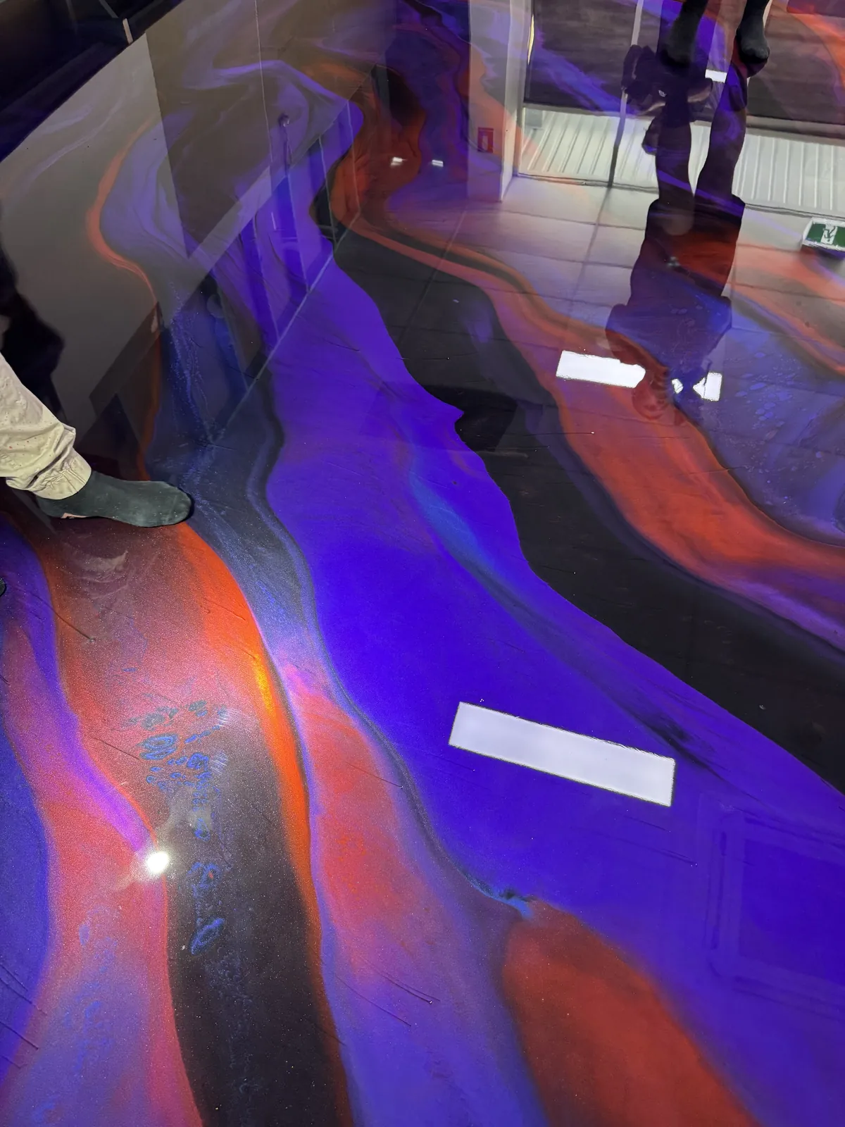 Purple, orange and black metallic epoxy floor with a mirror-like gloss reflecting the room