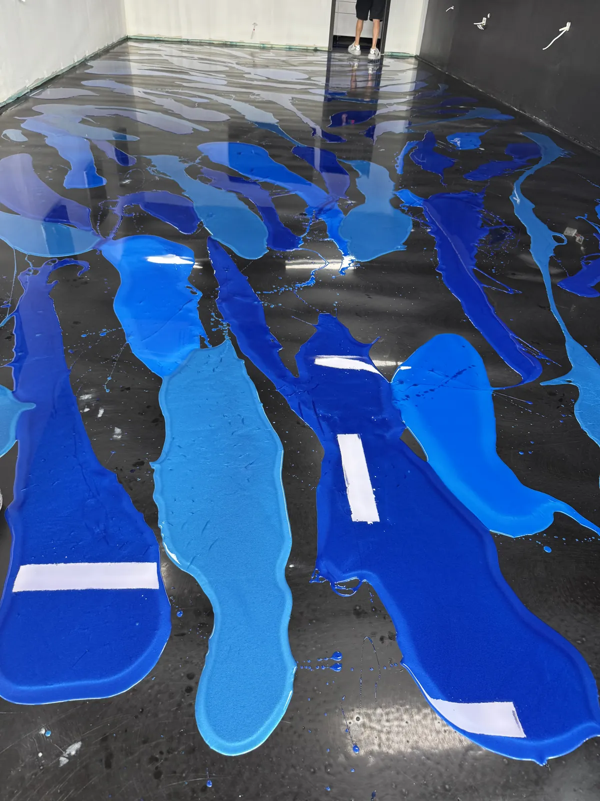 Two shades of blue metallic epoxy poured out across the floor, ready to be worked through by hand